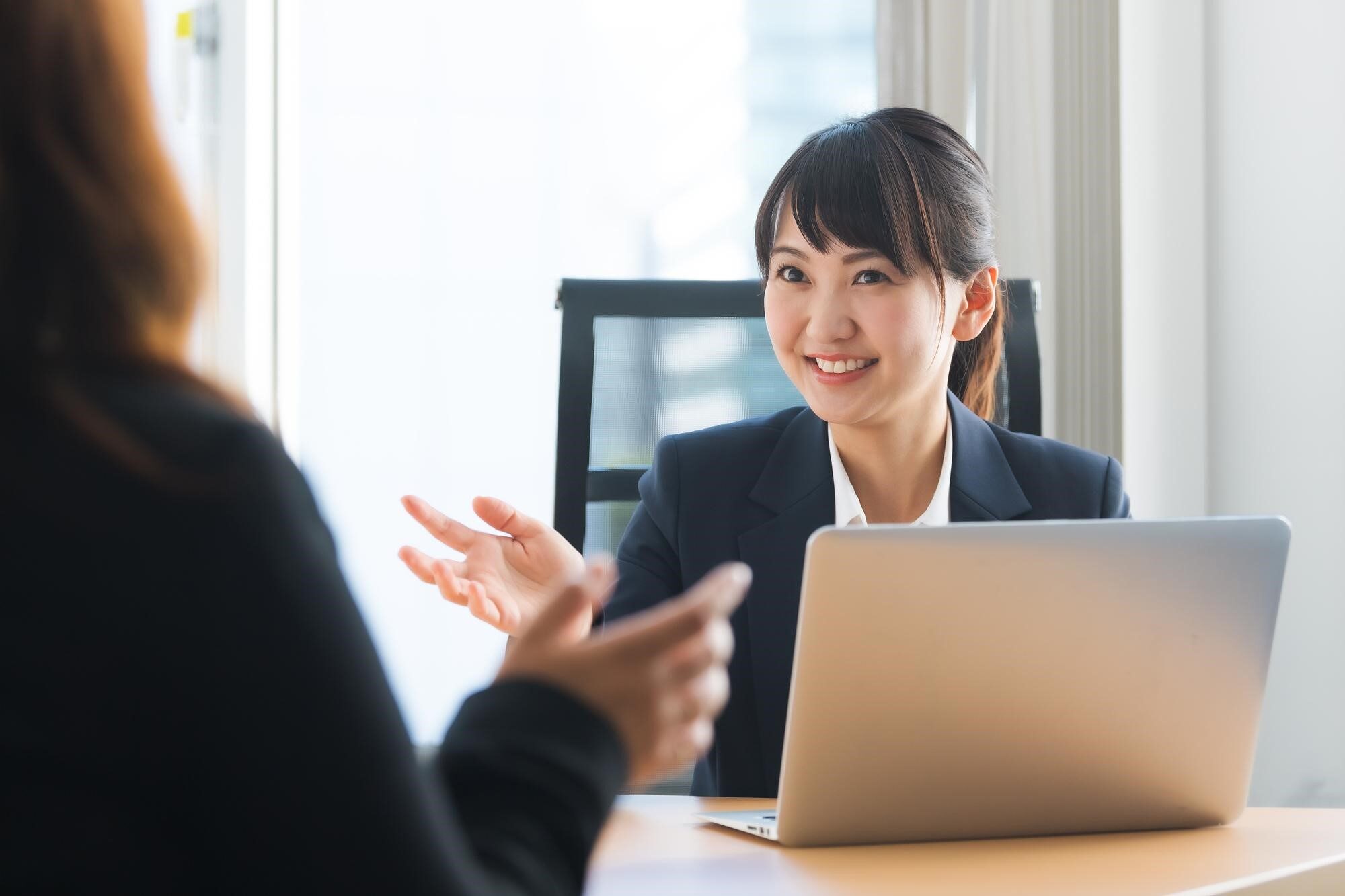 ノートPCを前に机を挟んで会話している2人の女性