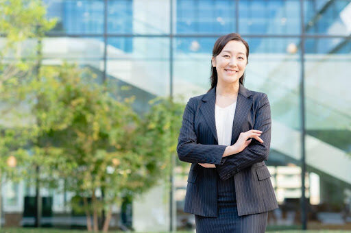 屋外で腕を組むスーツ姿の女性