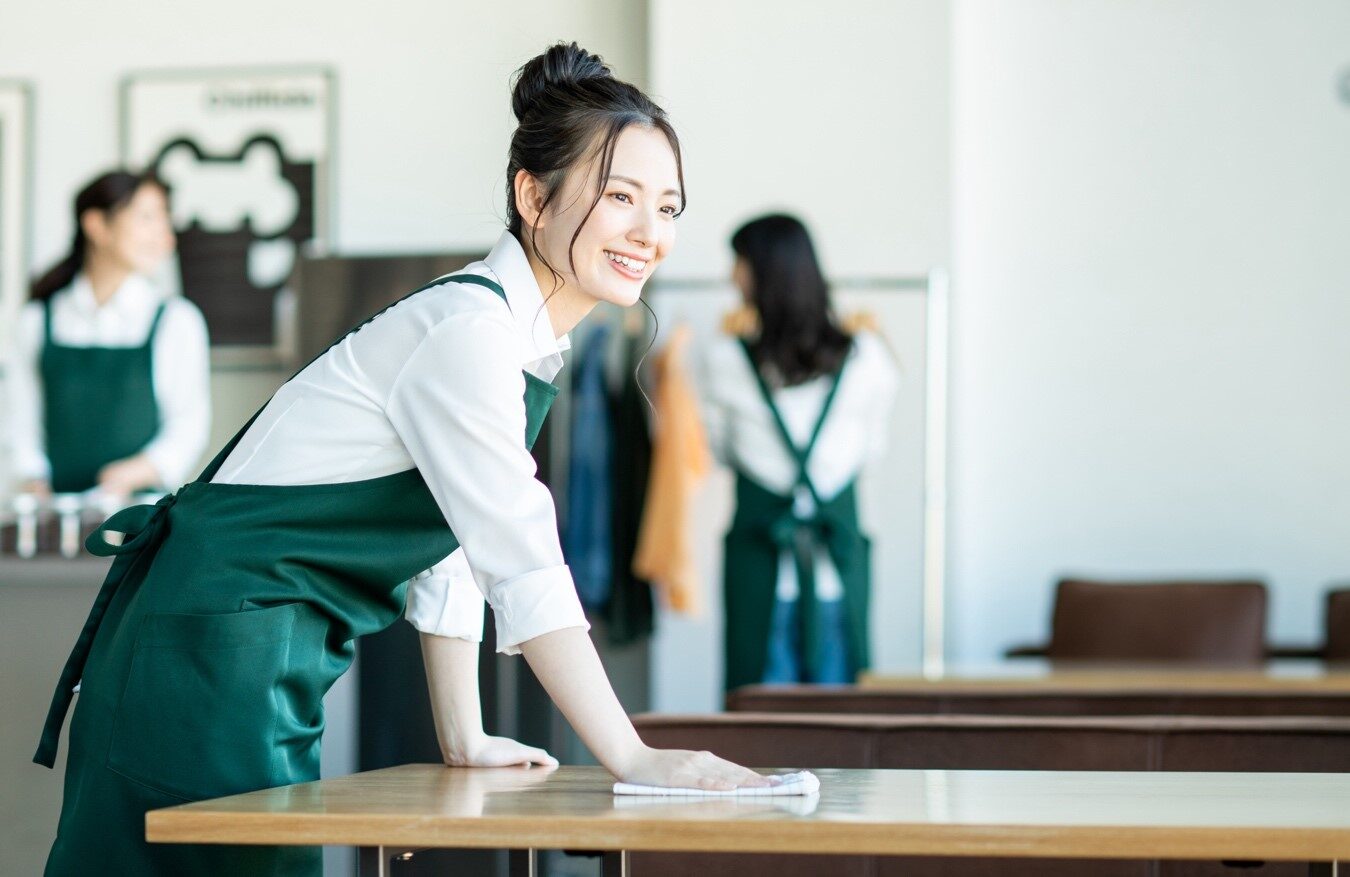 テーブルを拭くエプロン姿の女性