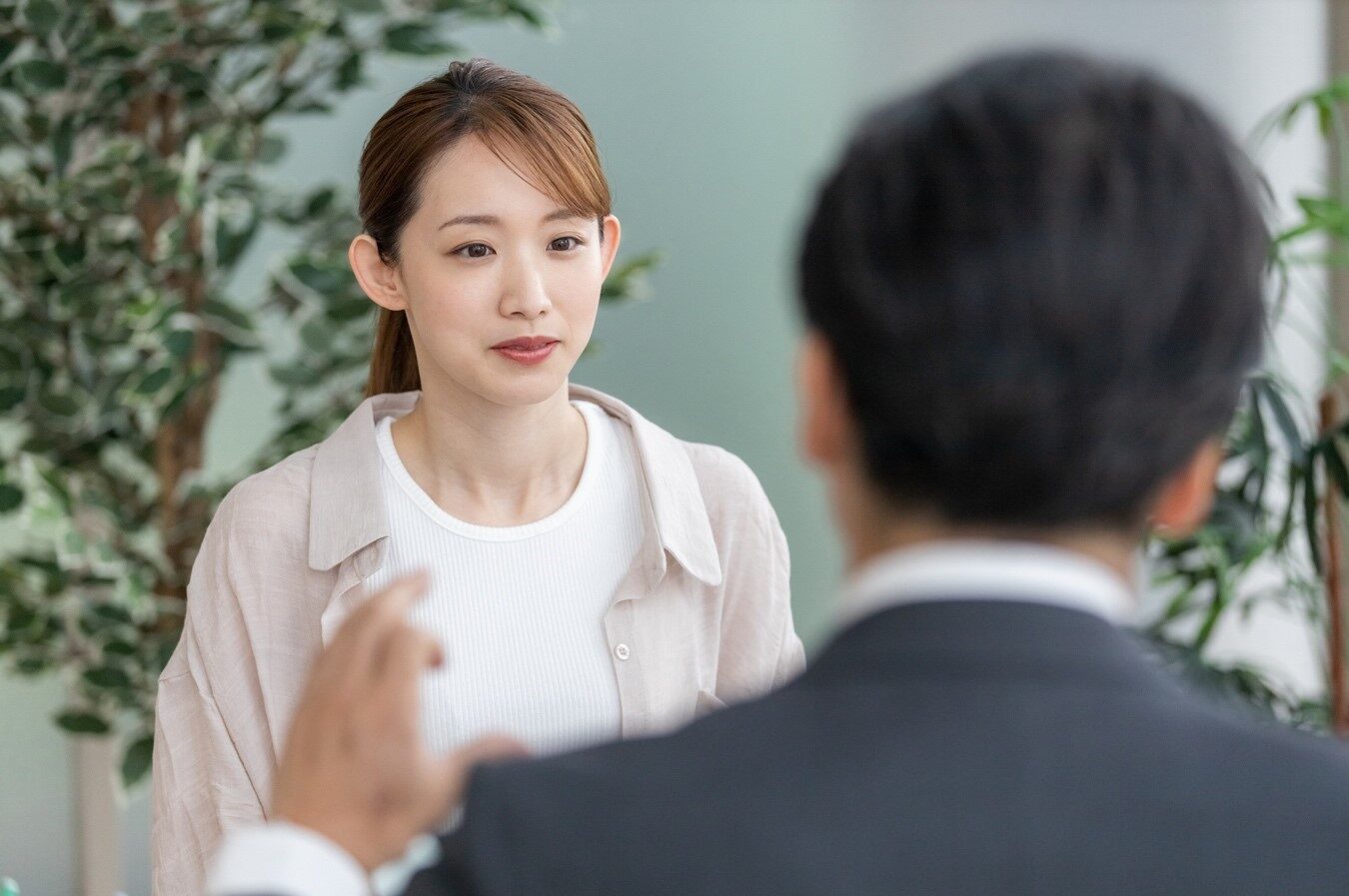 私服で面接を受ける女性と向かいで話す男性の後ろ姿