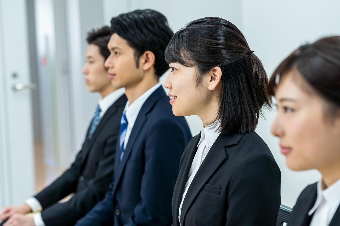 横に並んで座るスーツの男女4人